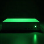 A single blank Zyxel-style network switch glowing green in the dark